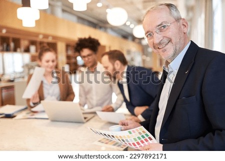 Businessman as successful manager with creative designer team on background