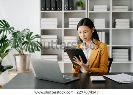Asian businesswoman working in the office with working notepad, tablet and laptop documents 