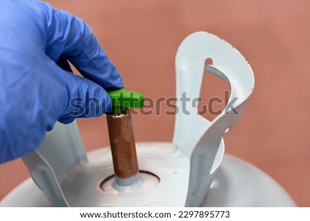 A Freon gas cylinder filled with colorless gas at room temperature, nonflammable, colorless, A refrigerant used in auto air conditioning and refrigeration system, cylinder valve and tube Royalty-Free Stock Photo #2297895773