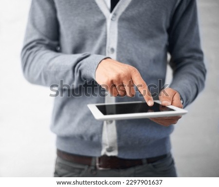Checking his emails on the go. Cropped image of a young man working on his digital tablet.