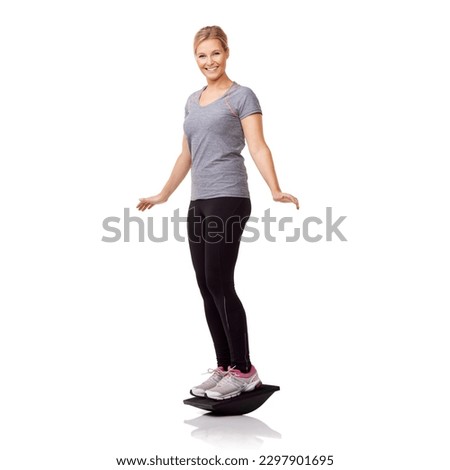 Balance improves her core. A pretty young woman exercising on a balance board while isolated on a white background.