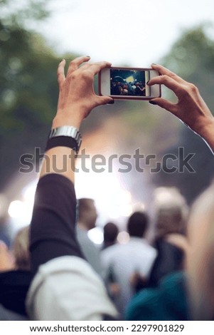 Capturing the awesome moment. A person taking a picture of their favourite band performing.