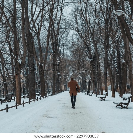 man in coat on city park path in winter
