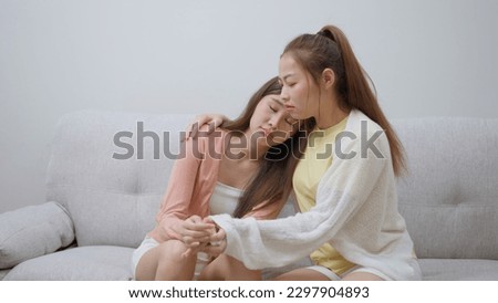 Two women talking about problems at home. Asian women embrace to calm their sad best friends from feeling down. Female friends supporting each other. Problems, friendship, and care concept Royalty-Free Stock Photo #2297904893