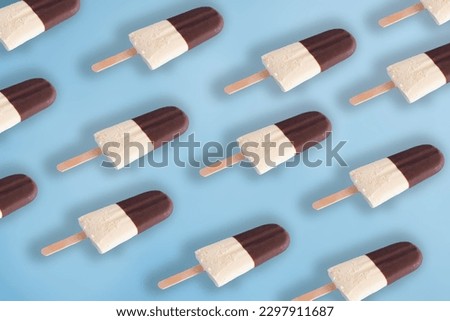 Trendy summer pattern made of black and white chocolate and milk ice cream on a pastel blue background. Minimal summer food concept.