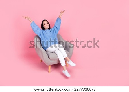 Full body photo of cheerful nice lady sit chair raise arms empty space ad isolated on pink color background