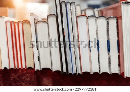Row of old aged books at flea market. Vintage retro literature print on display table outdoors. Street swap meet background. Second hand sale stuff literature and education Royalty-Free Stock Photo #2297972181