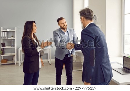 Two smiling male business partners shaking hands in office. Boss, team leader handshaking with happy male employee on staff meeting demonstrating respect, greeting Royalty-Free Stock Photo #2297975159