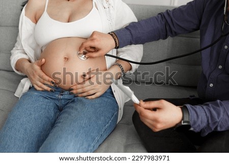 Pregnant woman visiting doctor hold ultrasound photo listen belly with stethoscope gynecology consultation tummy abdomen pregnancy check-up, maternity hospital

