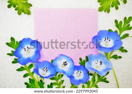 Mock-up of a lovely comment frame of pink Japanese paper decorated with baby blue eyes flowers on a white background of fabric.