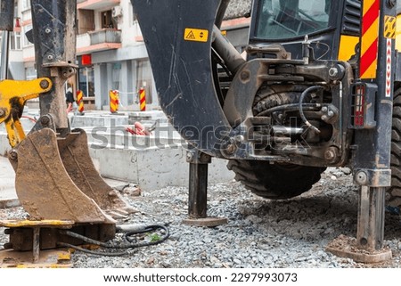 The work of public utilities on the laying of communications in the ground with the help of an earthmoving tractor in the center of the city . Royalty-Free Stock Photo #2297993073