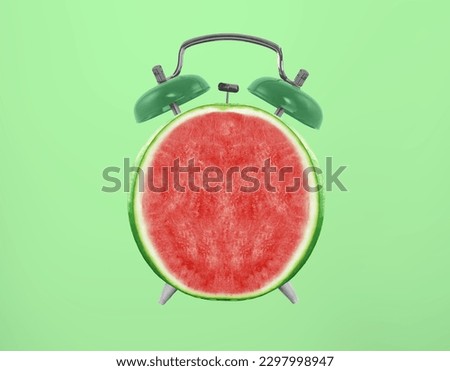 Delicious red watermelon with alarm clock on a green background, creative idea. Summer concept