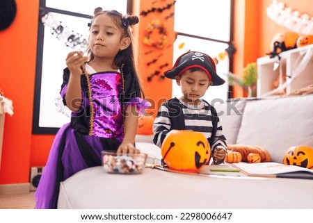 Adorable boy and girl having halloween party holding candies at home