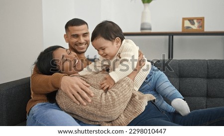 Couple and son hugging each other sitting on sofa at home Royalty-Free Stock Photo #2298010447