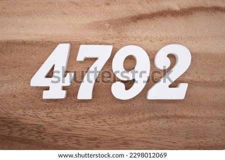 White number 4792 on a brown and light brown wooden background.