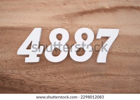 White number 4887 on a brown and light brown wooden background.