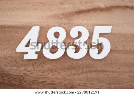 White number 4835 on a brown and light brown wooden background.