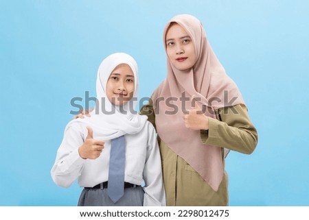 Muslim woman student with a teacher wearing school uniform isolated over blue background Royalty-Free Stock Photo #2298012475
