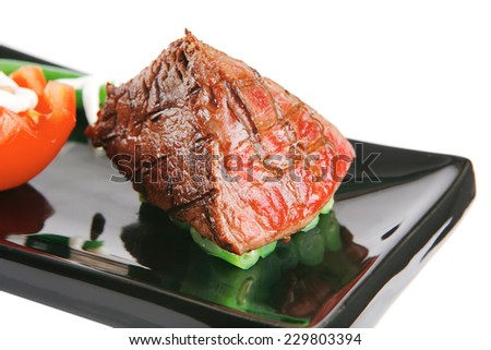 served roast veal fillet on a black plate with tomato