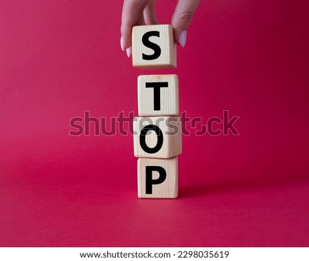 Stop symbol. Concept word Stop on wooden cubes. Businessman hand. Beautiful red background. Business and Stop concept. Copy space.