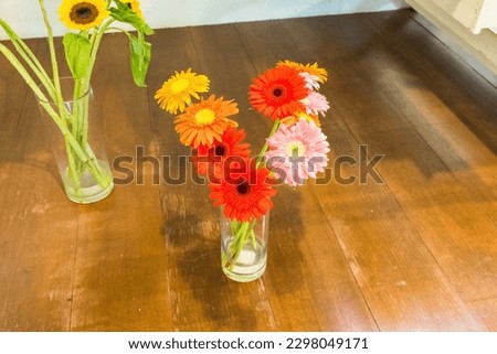 Sunflowers and rose in glass vase on wooden table.