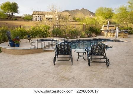 A desert landscaped backyard featuring a travertine pool deck and outdoor kitchen.
 Royalty-Free Stock Photo #2298069017