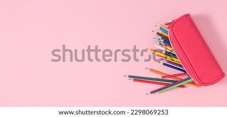 Back to school concept. Flat lay top view on pink full pencil case with pencils and pens isolated on pastel pink background banner Royalty-Free Stock Photo #2298069253