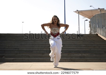 Latin woman, young and beautiful dancing modern dance in the street and makes different expressions and postures. Concept dance, hip hop, dance, art, action, beauty, youth art.