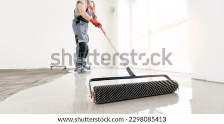 Master with needle roller for new screed concrete with self leveling cement mortar for floors. Concept building renovation home. Royalty-Free Stock Photo #2298085413