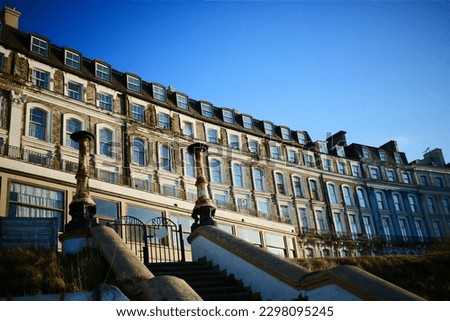 A terrace of faded Victorian seafront houses, evening light, blue sky. Margate, Kent. Royalty-Free Stock Photo #2298095245
