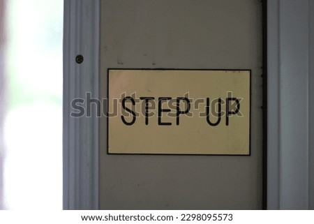 " STEP UP " Sign on the door of an Apartment leasing office in the US. Gold sign with black lettering. These kind of signs are common so people won't trip and fall from unexpected taller step.