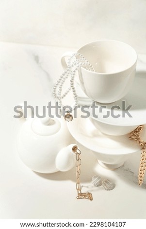 Tea set with stylish jewelry on white table