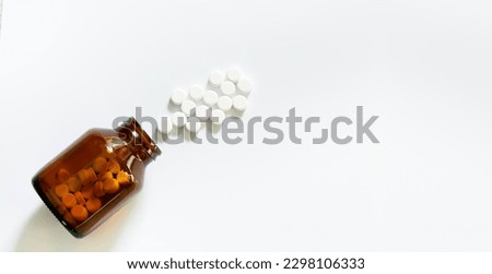 White pills and pill bottles,Medicine and a small bottle,Still life with pile of white pills or tablets and glass bottle or glass and space for text Royalty-Free Stock Photo #2298106333