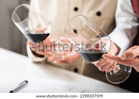 Red wine tasting. Participants compare the colors of different red wines in a wine tasting event, learning to identify the wine's age, grape varietal, and other key details based on hue. Royalty-Free Stock Photo #2298107599