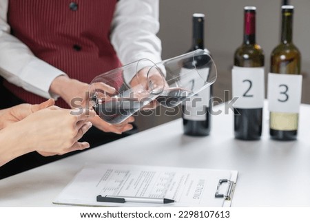 Red wine tasting. Participants compare the colors of different red wines in a wine tasting event, learning to identify the wine's age, grape varietal, and other key details based on hue. Royalty-Free Stock Photo #2298107613