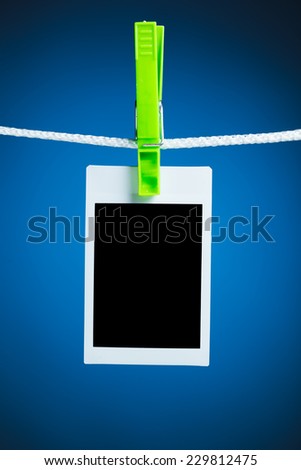 blank photo hanging on rope, blue background