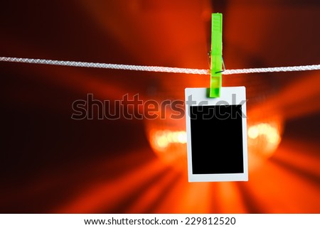 blank photo hanging on rope, orange lights background
