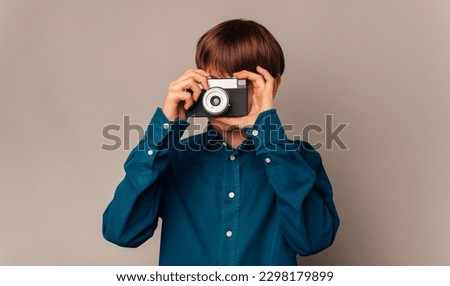 Handsome teen boy in blue shirt is looking through his old vintage camera.