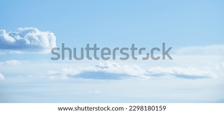 White fluffy clouds on a summer blue sky in cartoon style for background or wallpaper design. The background is white of round clouds in a blue sky.