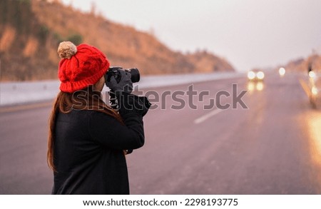 A young Girl Capturing Something with DSLR Camera on the Road in Winter