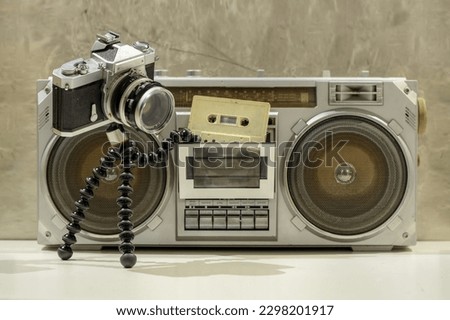 An old camera putting cassette into a boombox  