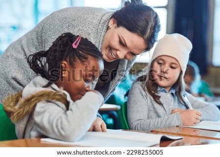 Dedicated in helping her students understand the work. elementary school girls getting help from their teacher in the classroom. Royalty-Free Stock Photo #2298255005