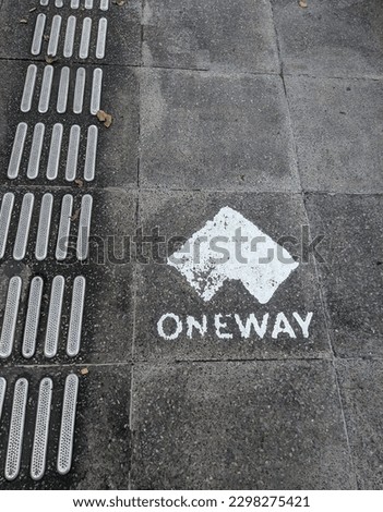 One way sign on the sidewalk. One way sign for pedestrians