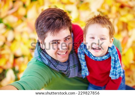 happy father and son making selfie among fallen leaves