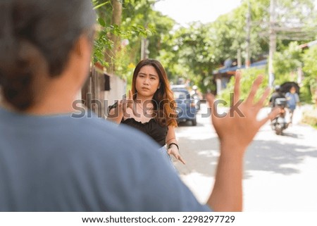 A brave young asian woman confronts a creepy stalker following her while walking. Courageously standing up to harassment. Royalty-Free Stock Photo #2298297729