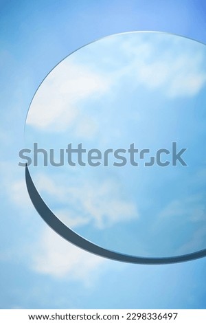 Abstract minimal scene with round mirror placed on blue background. The mirror reflects the clear blue sky and white clouds. Copy space Royalty-Free Stock Photo #2298336497