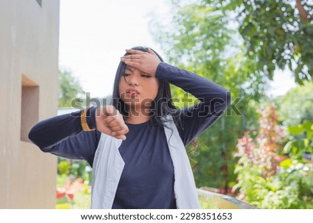 A young asian woman facepalms while checking her wristwatch. Late for a date, school or work. Royalty-Free Stock Photo #2298351653