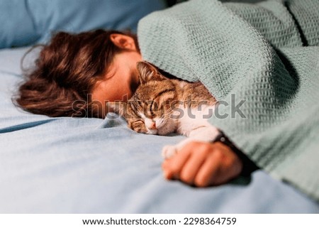 boy falls asleep and hugs his cat, who sleeps with him under the covers. children and pets. the cat sleeps with the baby. the child is getting ready for bed. Royalty-Free Stock Photo #2298364759