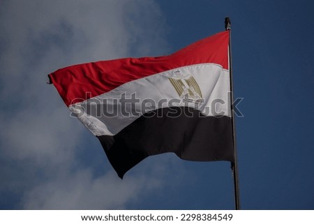 Egypt flag, red white and black horizontal stripes with golden eagle in the center