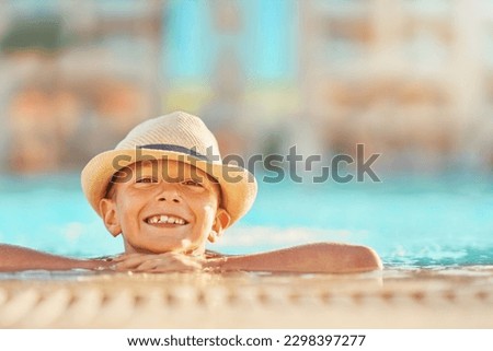 Picture of young boy in hat playing in outdoor swimming pool